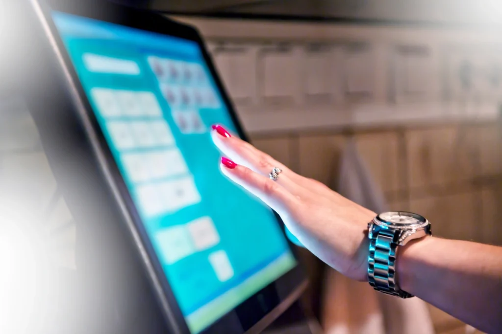 Close-up of a person’s hand reaching toward a touchscreen monitor, demonstrating modern technology that could integrate with POTS Line Replacement systems.