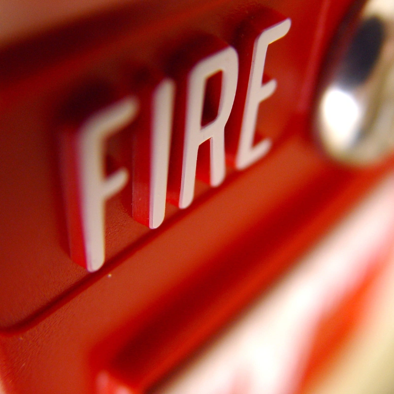 Close-up of the word “FIRE” on a red fire alarm device, highlighting emergency alert systems that rely on POTS Line Replacement.